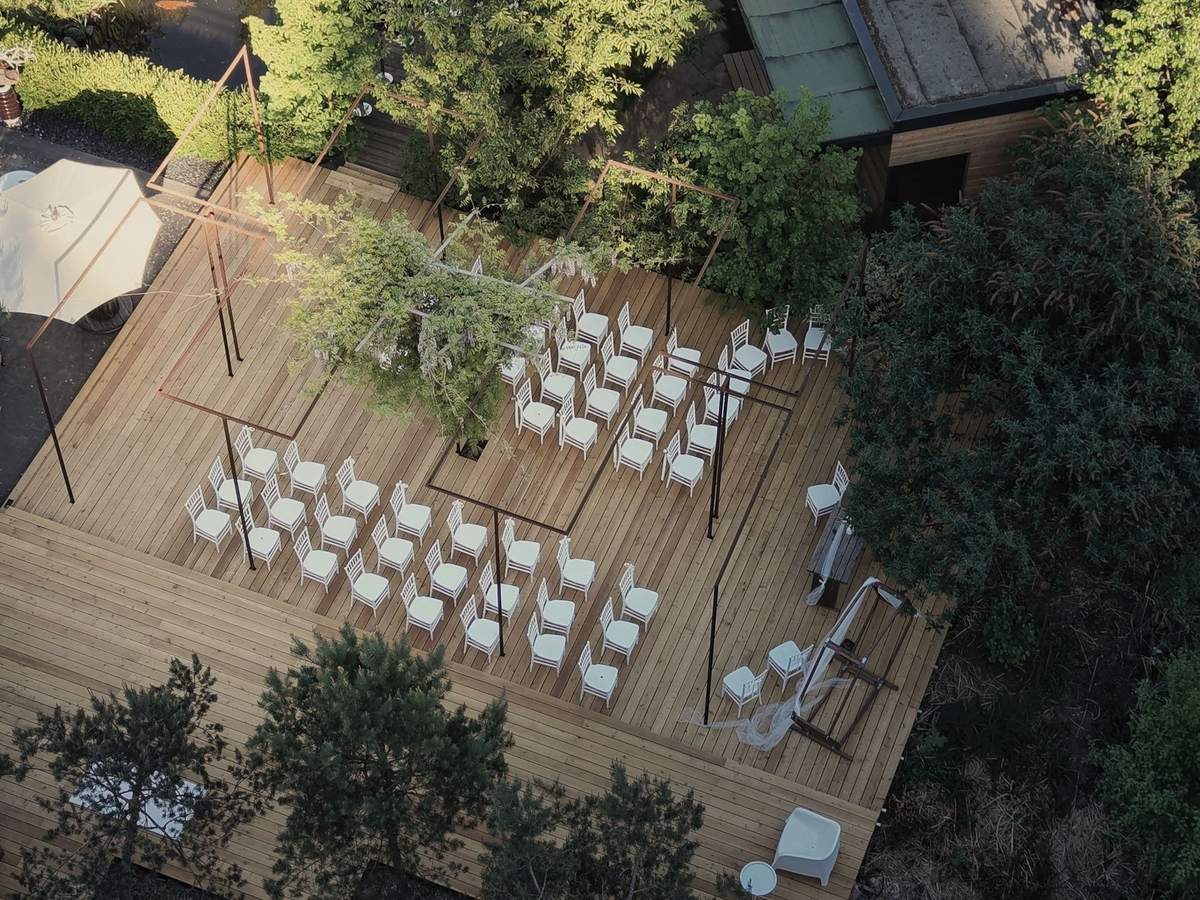 Holzterrasse im Garten von oben, mit weißen Stühlen für eine freie Trauung